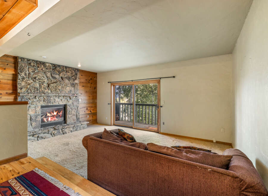 Cozy living room featuring a rustic stone fireplace with a roaring fire, complemented by warm wood paneling.