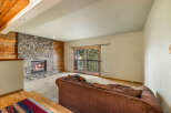 Cozy living room featuring a rustic stone fireplace with a roaring fire, complemented by warm wood paneling.