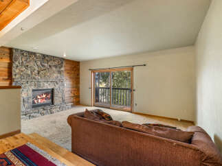 Cozy living room featuring a rustic stone fireplace with a roaring fire, complemented by warm wood paneling.