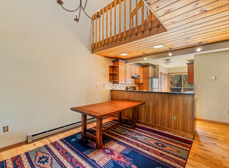 Experience rustic charm in this inviting dining area, featuring a warm wooden table and a vibrant Southwestern-style rug.