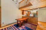Experience rustic charm in this inviting dining area, featuring a warm wooden table and a vibrant Southwestern-style rug.