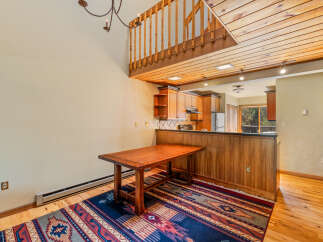 Experience rustic charm in this inviting dining area, featuring a warm wooden table and a vibrant Southwestern-style rug.