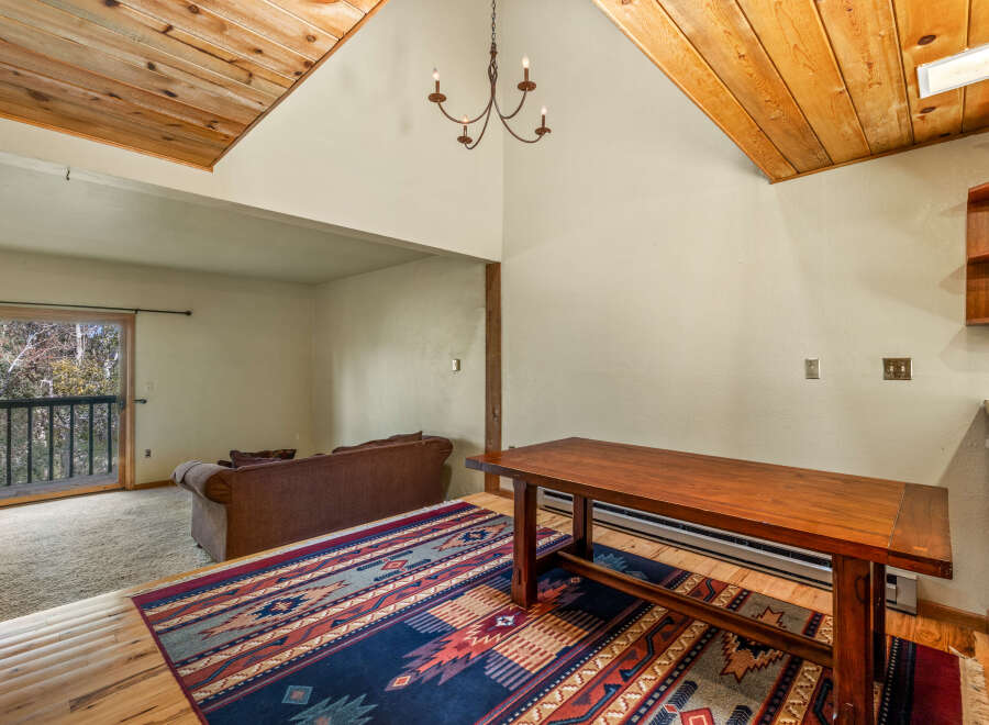 Experience rustic charm in this inviting living space, featuring a vaulted wood-paneled ceiling and a cozy seating area.