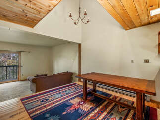 Experience rustic charm in this inviting living space, featuring a vaulted wood-paneled ceiling and a cozy seating area.