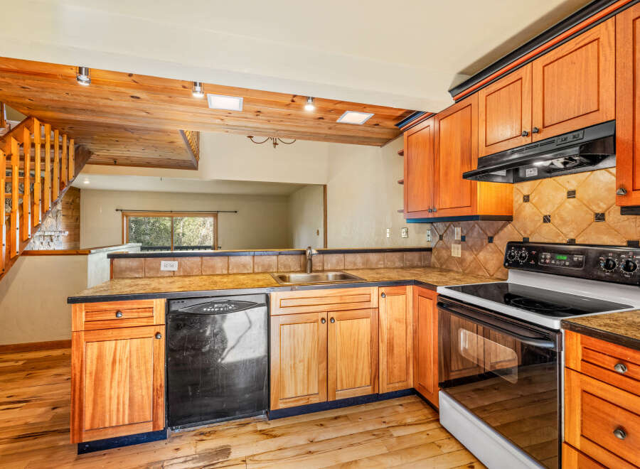 This charming kitchen features warm wooden cabinetry and a rustic stone accent wall leading to a staircase.