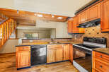 This charming kitchen features warm wooden cabinetry and a rustic stone accent wall leading to a staircase.
