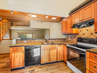 This charming kitchen features warm wooden cabinetry and a rustic stone accent wall leading to a staircase.