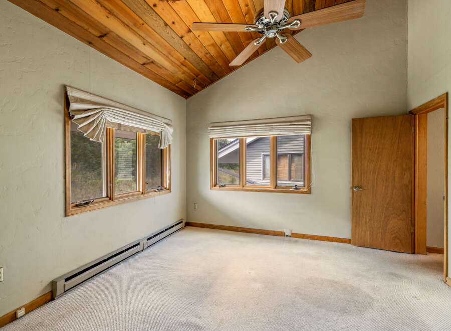 This charming bedroom features a vaulted wood-paneled ceiling and a ceiling fan, creating a warm and inviting atmosphere.