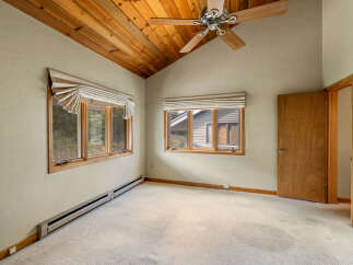 This charming bedroom features a vaulted wood-paneled ceiling and a ceiling fan, creating a warm and inviting atmosphere.