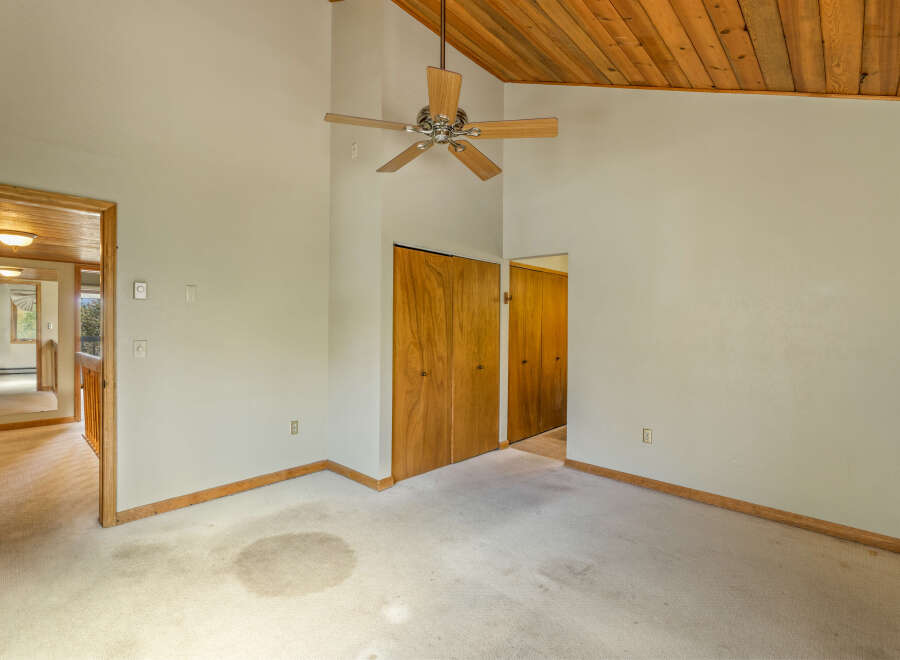 Discover a spacious room with vaulted wood-paneled ceilings and a ceiling fan, perfect for creating a cozy atmosphere.