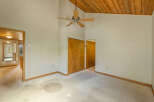 Discover a spacious room with vaulted wood-paneled ceilings and a ceiling fan, perfect for creating a cozy atmosphere.
