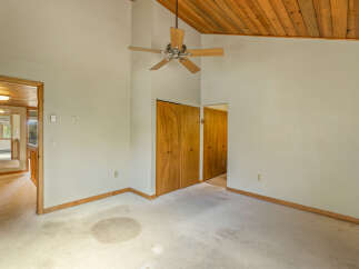 Discover a spacious room with vaulted wood-paneled ceilings and a ceiling fan, perfect for creating a cozy atmosphere.