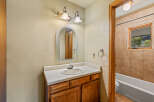 This charming bathroom features a wooden vanity with a white countertop and a sleek faucet, complemented by an arched mirror above.