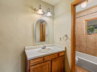 This charming bathroom features a wooden vanity with a white countertop and a sleek faucet, complemented by an arched mirror above.