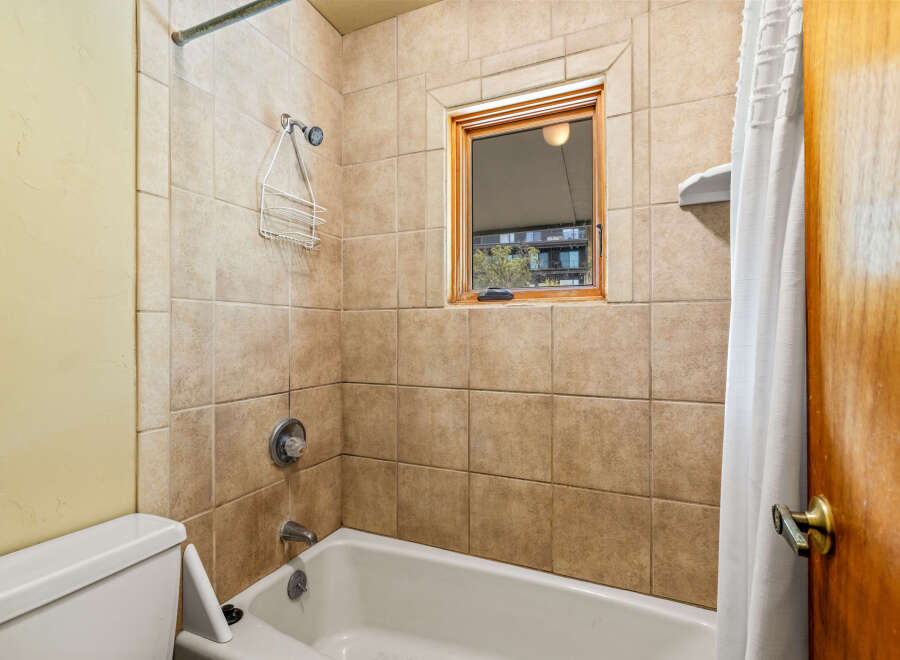 This bathroom features a classic tiled shower and tub combination, perfect for relaxing baths or quick showers.