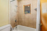 This bathroom features a classic tiled shower and tub combination, perfect for relaxing baths or quick showers.