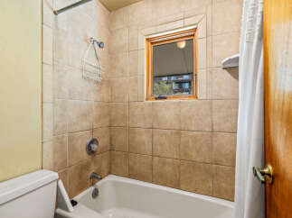 This bathroom features a classic tiled shower and tub combination, perfect for relaxing baths or quick showers.