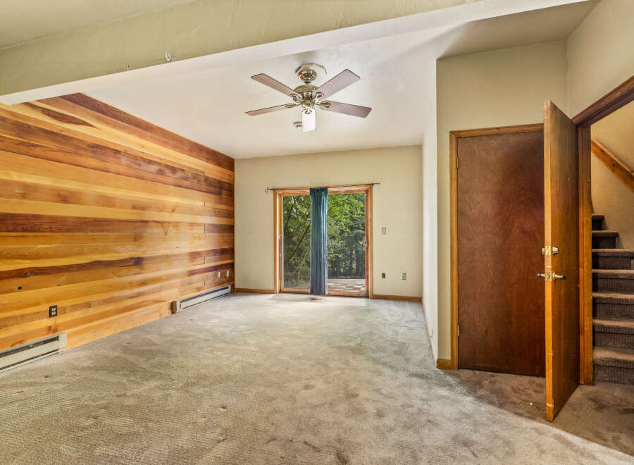 This spacious living area features a striking accent wall of warm wood paneling, creating a cozy and inviting atmosphere.