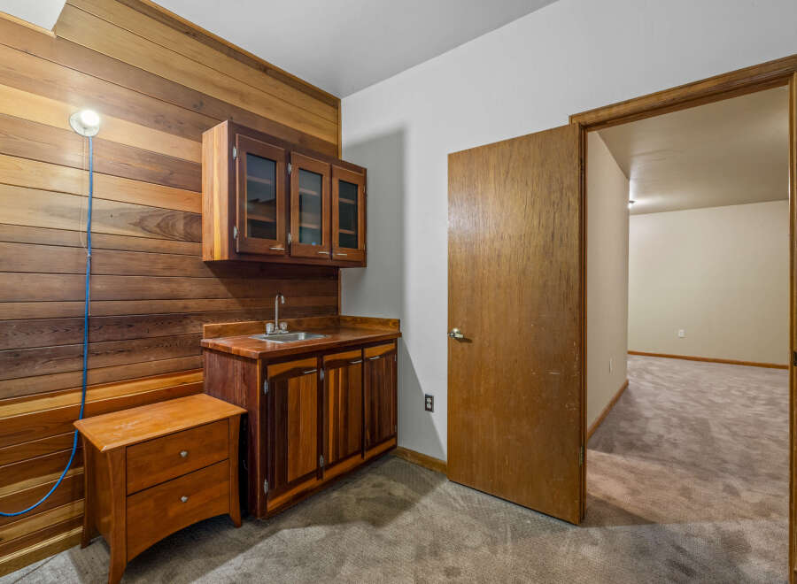 Discover this charming space featuring a built-in wet bar with rich wooden cabinetry and a stainless steel sink, perfect for entertaining.