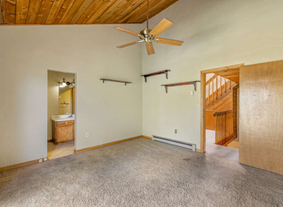 Step into this charming room featuring a vaulted wood-paneled ceiling and a ceiling fan for optimal comfort.