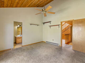 Step into this charming room featuring a vaulted wood-paneled ceiling and a ceiling fan for optimal comfort.