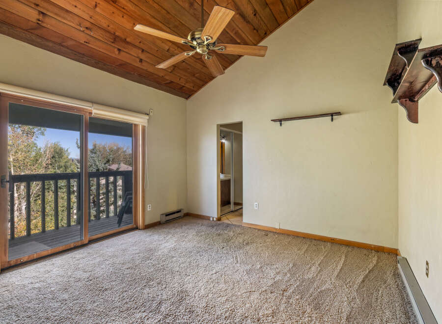 Experience breathtaking views from this spacious room featuring a vaulted wood-paneled ceiling and a convenient sliding glass door leading to a private balcony.