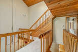 Ascend to the upper level of this charming home via the beautifully crafted wooden staircase, featuring a warm, natural wood finish.