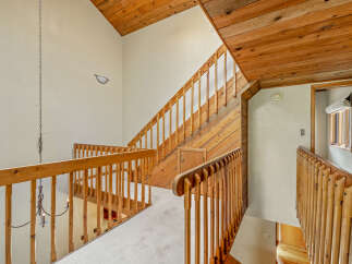 Ascend to the upper level of this charming home via the beautifully crafted wooden staircase, featuring a warm, natural wood finish.