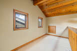Discover this charming attic space featuring a vaulted wooden ceiling and two inviting windows that offer natural light.