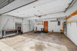 Discover the potential of this spacious garage, featuring a durable concrete floor and ample overhead storage with sturdy wooden shelves.