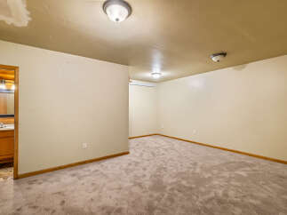 Discover the potential in this spacious room, featuring a neutral carpet and a convenient doorway leading to a well-appointed bathroom.
