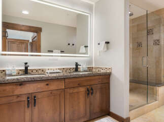 Experience luxury in this stunning bathroom featuring a spacious double vanity with granite countertops and modern black fixtures.