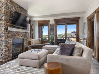 Experience luxury mountain living in this stunning living room, featuring a grand stone fireplace and a large, comfortable sectional sofa perfect for cozy evenings.