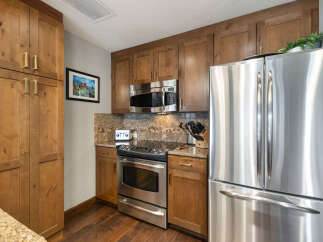 This kitchen features beautiful wooden cabinetry and sleek stainless steel appliances, including a refrigerator, oven, and microwave.