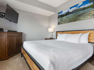 Experience ultimate comfort in this beautifully appointed bedroom, featuring a king-size bed with crisp white linens and plush pillows.