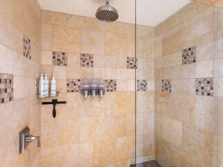 Experience luxury in this beautifully tiled shower featuring a rainfall showerhead and convenient built-in dispensers for shampoo and conditioner.