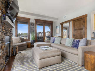 Experience luxury mountain living in this stunning living room, featuring a grand stone fireplace and a spacious sectional sofa perfect for cozy evenings.