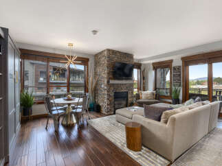 Experience modern mountain living in this stunning open-concept living space, featuring a striking stone fireplace and a stylish dining area perfect for intimate gatherings.