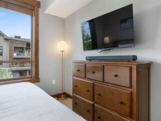Experience modern comfort in this bedroom, featuring a large flat-screen TV mounted above a classic wooden dresser.