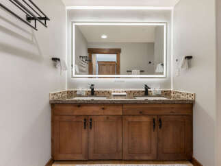 This modern bathroom features a spacious double vanity with granite countertops and a decorative mosaic backsplash.
