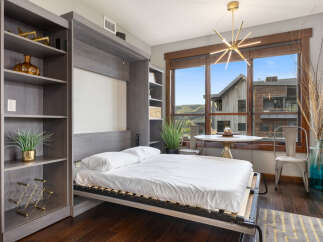 Experience modern living in this studio apartment featuring a space-saving Murphy bed and integrated shelving.