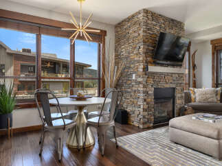 Experience modern mountain living in this stunning great room, featuring a floor-to-ceiling stone fireplace and expansive windows with breathtaking views.