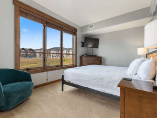 Experience comfort and style in this inviting bedroom, featuring a plush teal armchair perfect for relaxation.