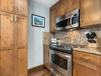 This charming kitchen boasts beautiful natural wood cabinetry complemented by sleek stainless steel appliances, including a microwave and oven.