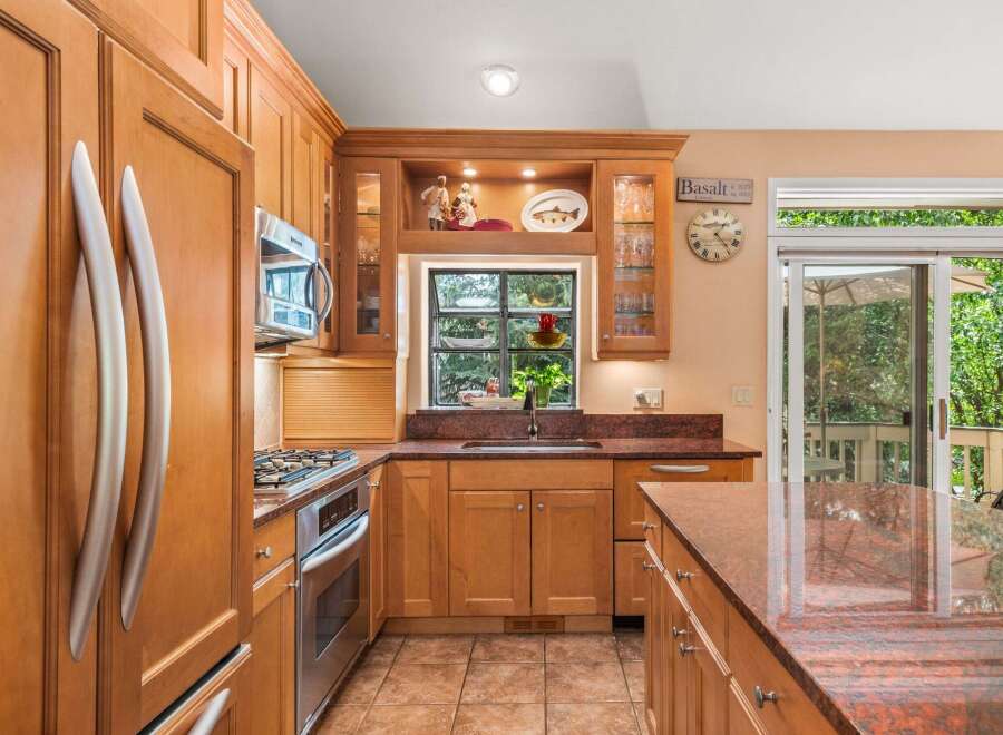 This spacious kitchen boasts beautiful cherry wood cabinetry and granite countertops, offering a warm and inviting atmosphere.