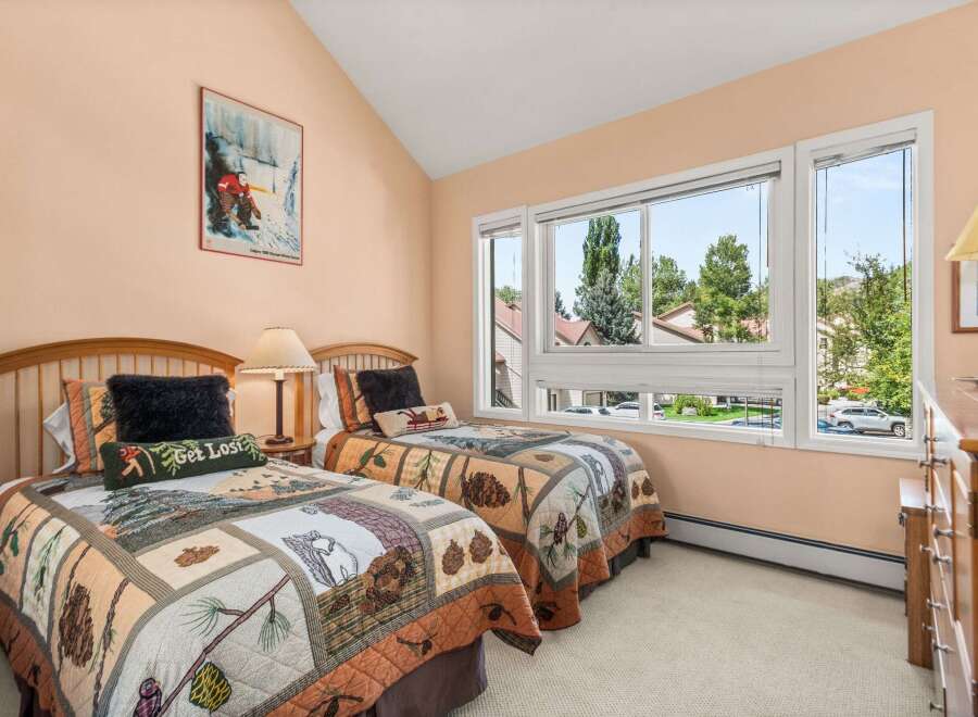 This charming bedroom features two cozy twin beds adorned with nature-themed quilts, perfect for a restful night's sleep.