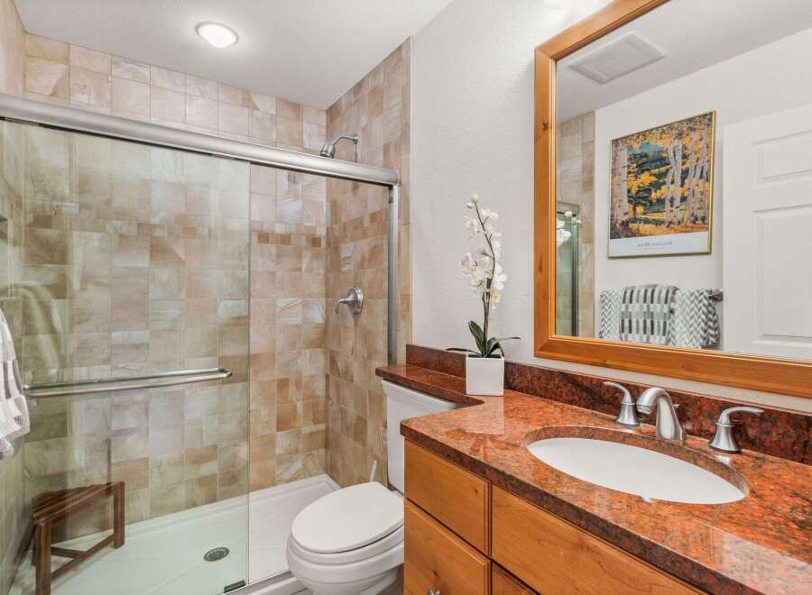 This bathroom features a spacious walk-in shower with elegant tile work and a convenient wooden bench.