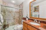 This bathroom features a spacious walk-in shower with elegant tile work and a convenient wooden bench.