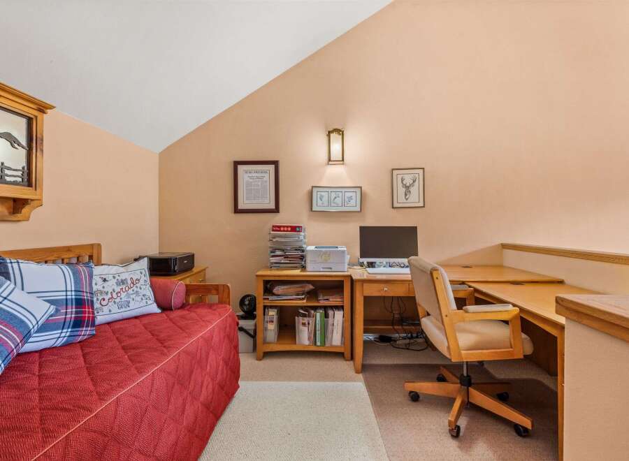 This charming room features a comfortable red daybed adorned with decorative pillows, perfect for relaxation or as an extra sleeping space.
