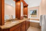This elegant bathroom features a spacious double vanity with granite countertops and rich cherry wood cabinetry.
